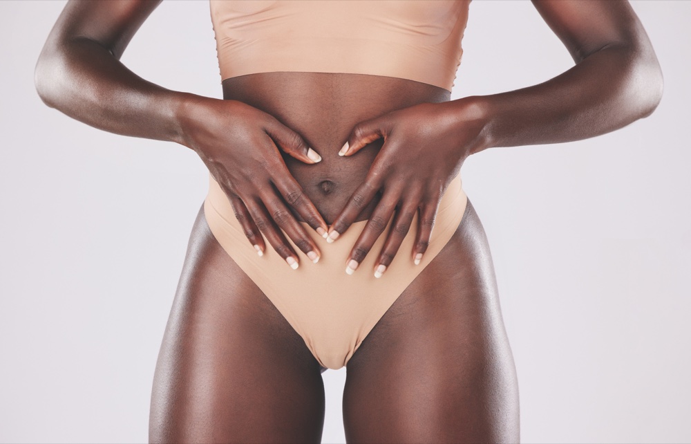 Torso de una mujer en ropa interior que forma un corazón con las manos sobre el vientre
